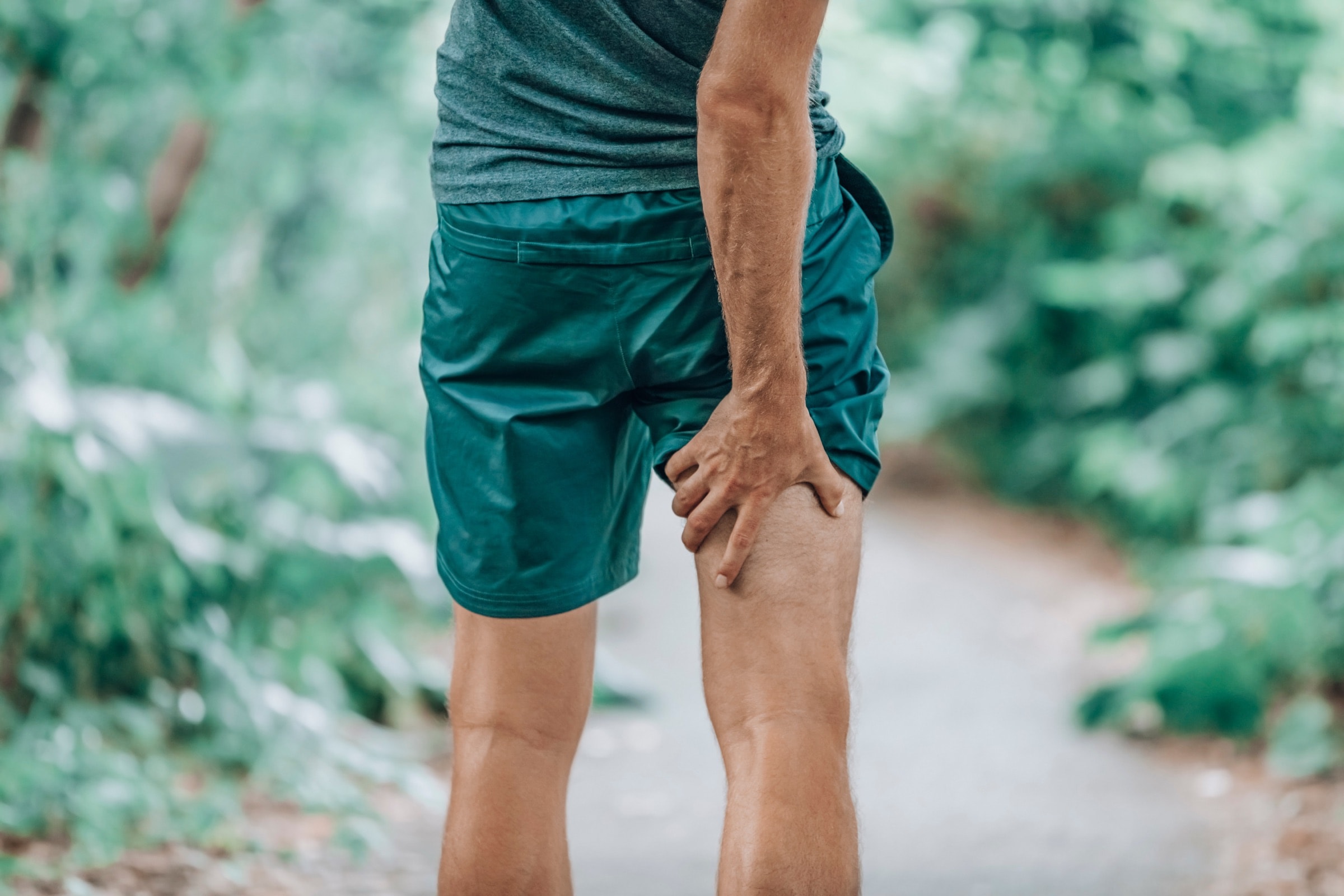 A runner on a trail holding the back of his thigh