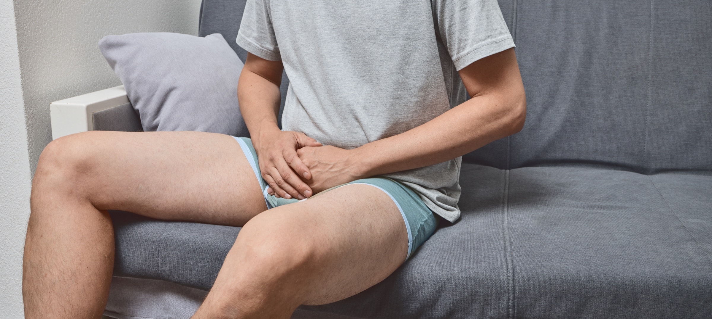 Man on a sofa with pelvic discomfort