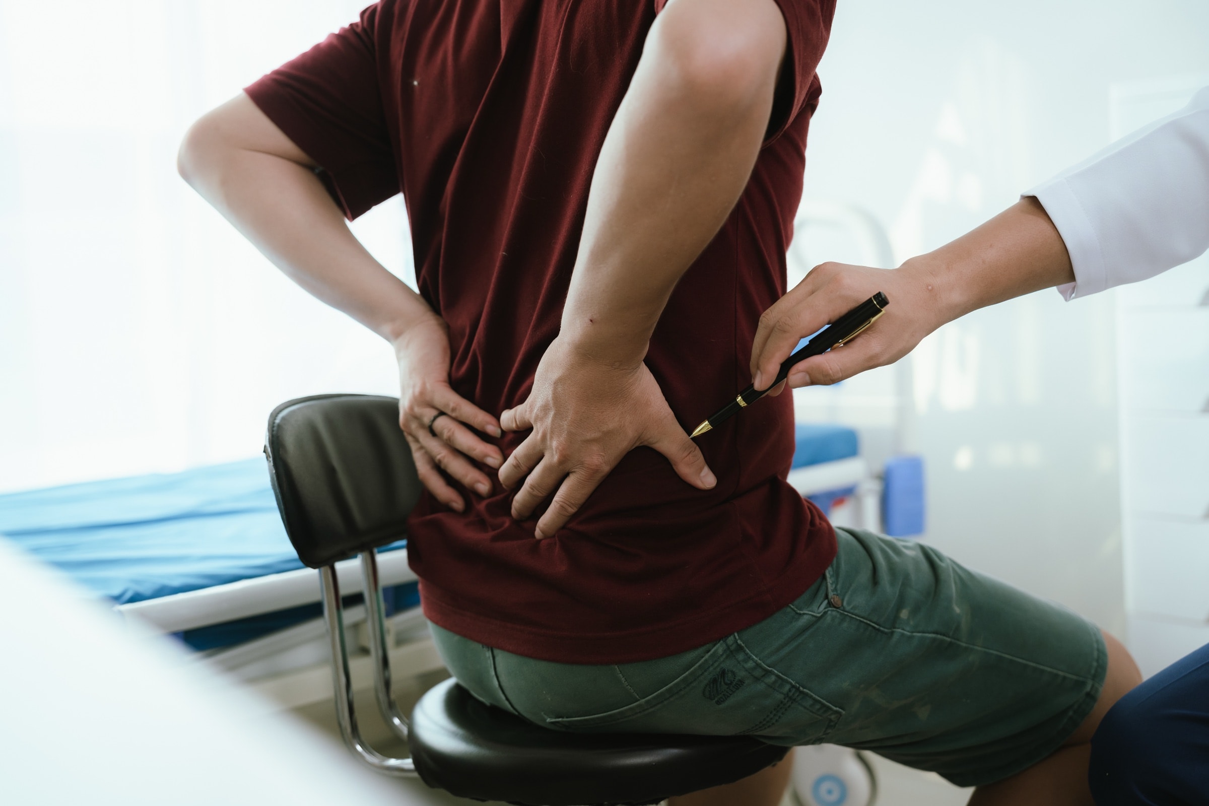 A clinician pointing to the lower back of a male patient