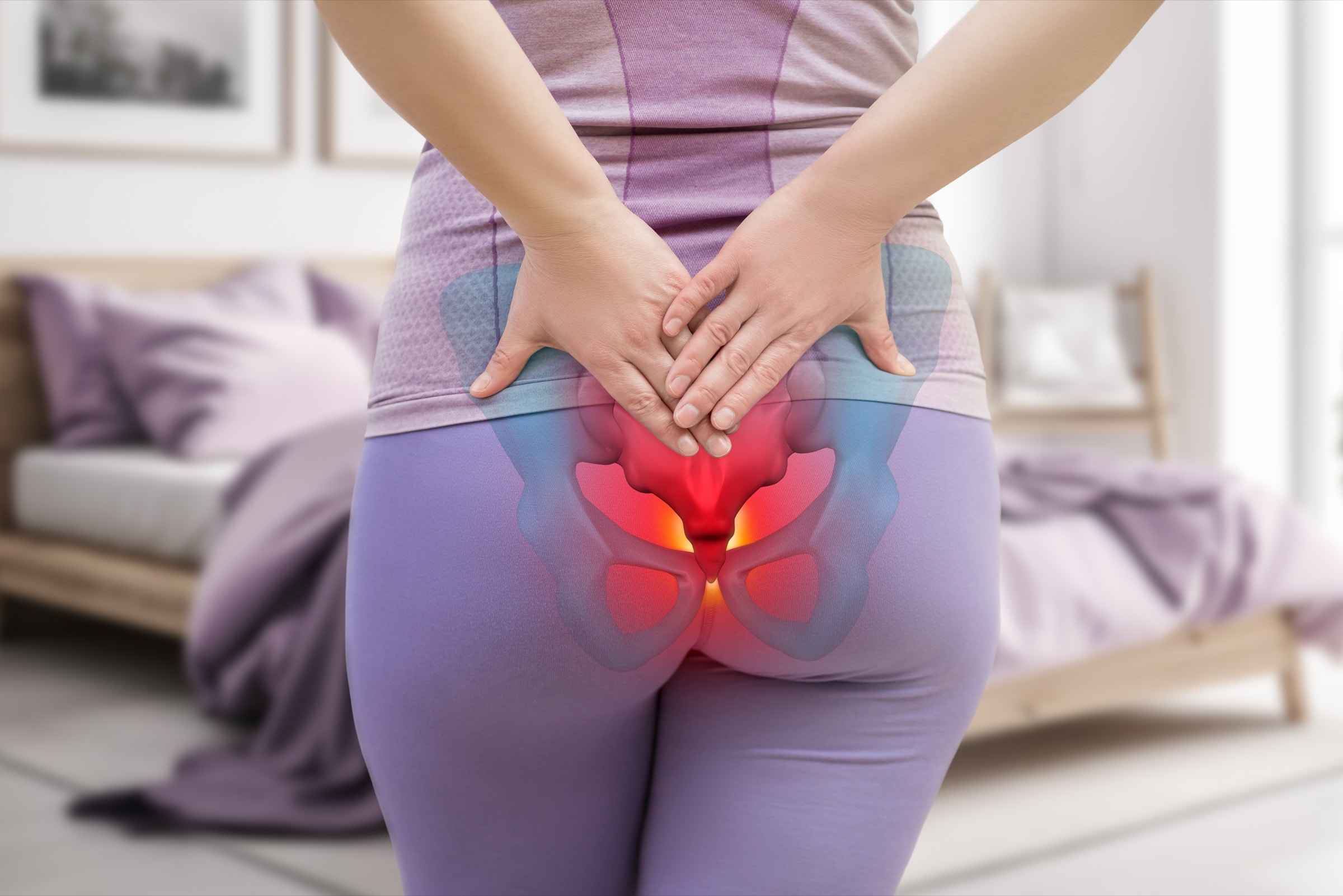 A woman holding her lower back with the tailbone area highlighted